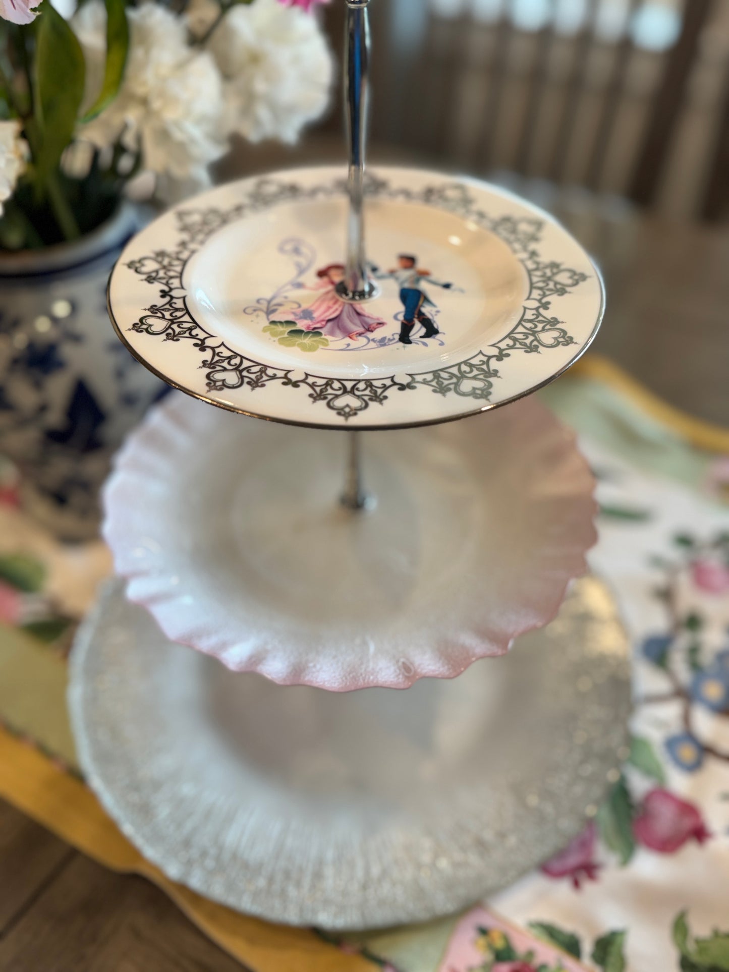 Three-tiered stand with romantic prince and princess plate, pink scalloped center plate, and clear glass bottom tier with silver handle