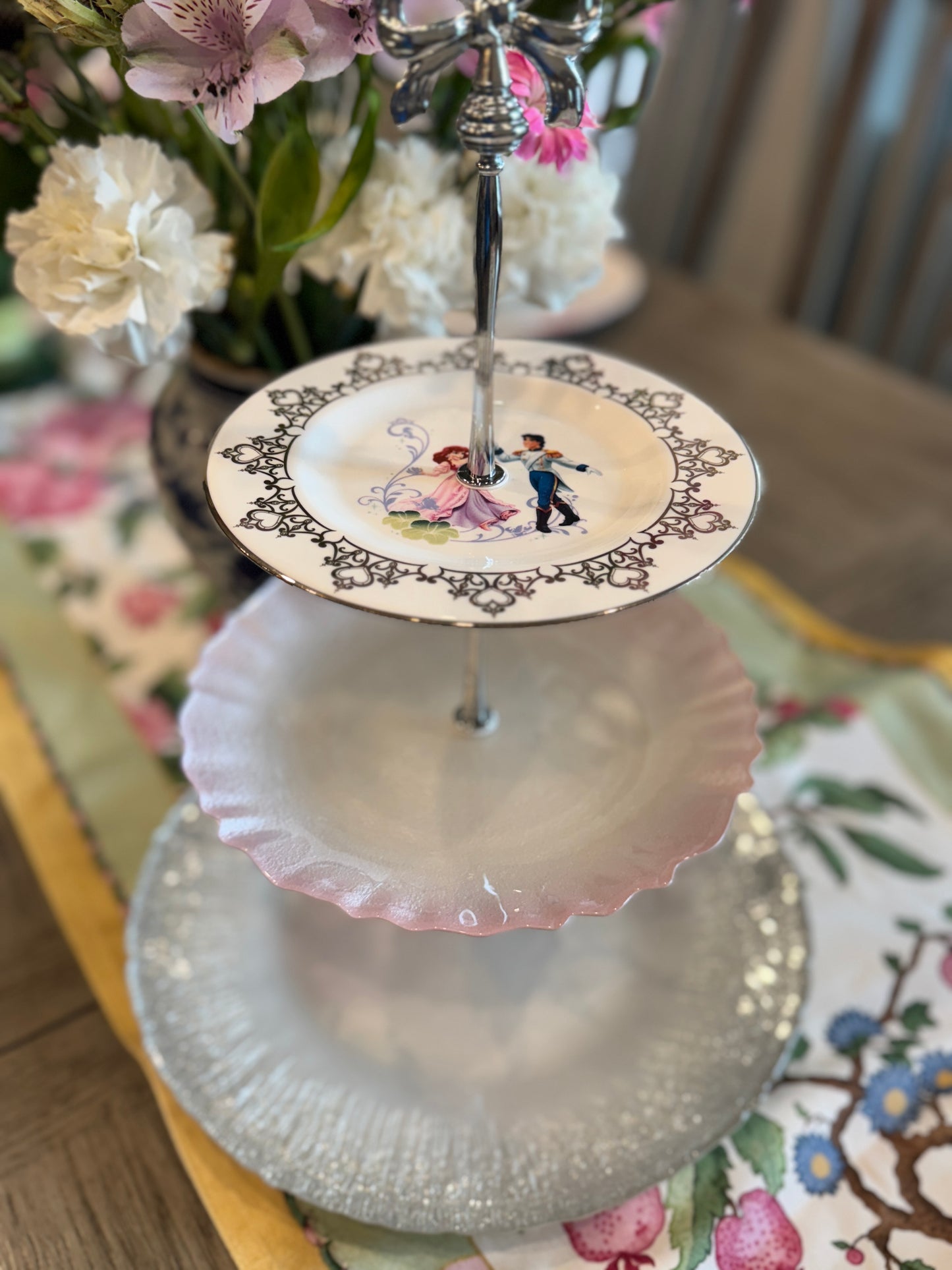 Three-tiered stand with romantic prince and princess plate, pink scalloped center plate, and clear glass bottom tier with silver handle