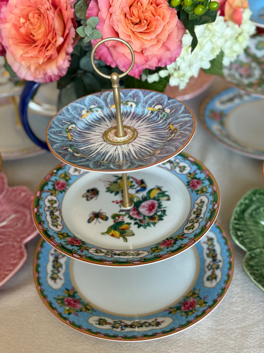Custom Three-tiered decorative plate with floral and bird patterns on a table with flowers in the background.