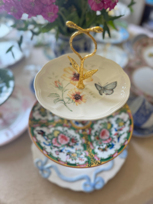 Three-tier serving stand with Lenox Butterfly Meadow plate on top, Famille Rose china in the middle, and Anthropologie bow plate on the bottom, gold hardware, all new plates.