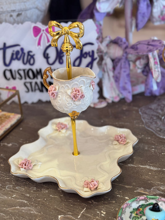 Vintage vanity stand with pink rose chintz teacup and scalloped tray, accented with delicate floral details.